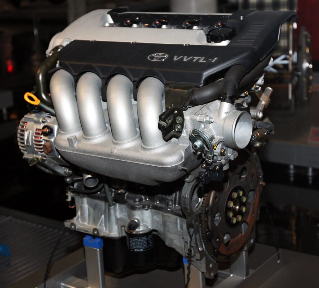 Toyota 2ZZ-GE engine with a black VVTL-i cover and a silver intake manifold on a display stand