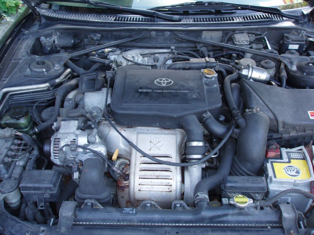 Engine bay of a Toyota Celica GT-Four ST205 with the black intake cover of the 3S-GTE turbo engine