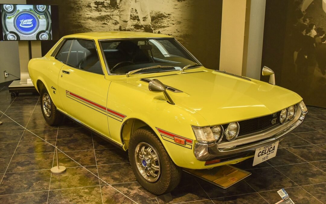 Yellow 1970 Toyota Celica coupé with GT stripes on display in a museum hall