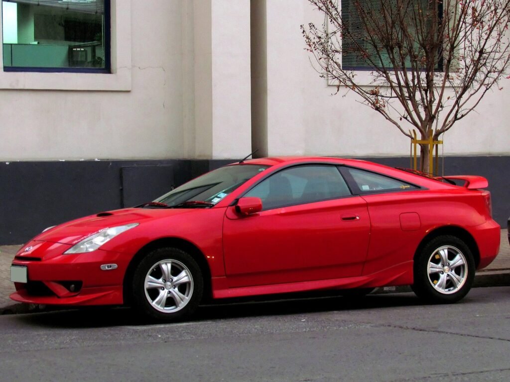 Red seventh-generation Toyota Celica parked in front of a white building
