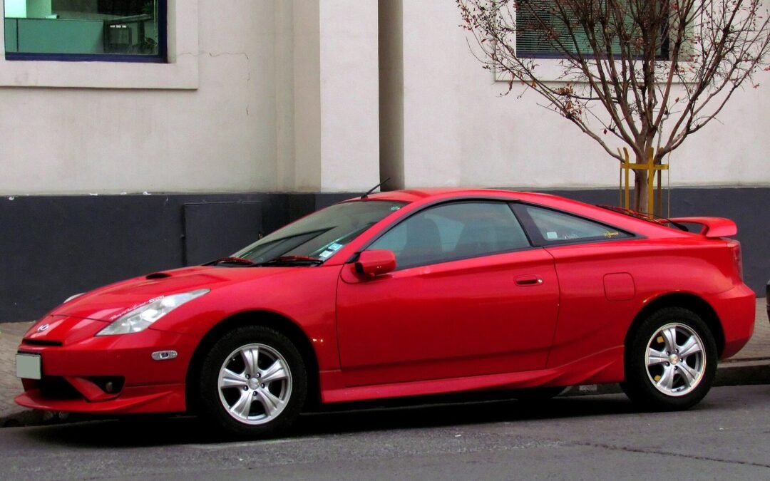 Red seventh-generation Toyota Celica parked in front of a white building
